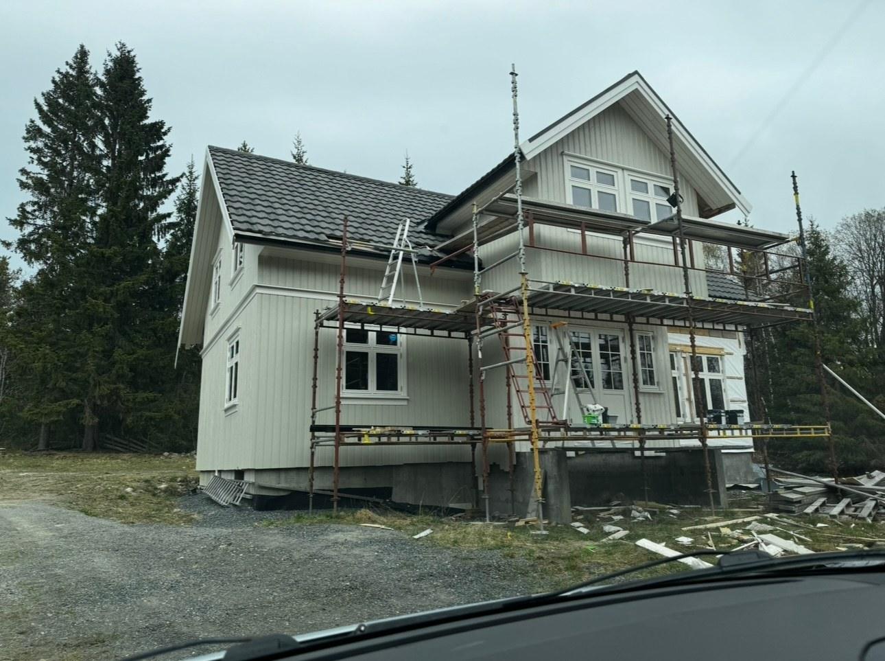 A white two-storey house in scaffolding while its facade is redone