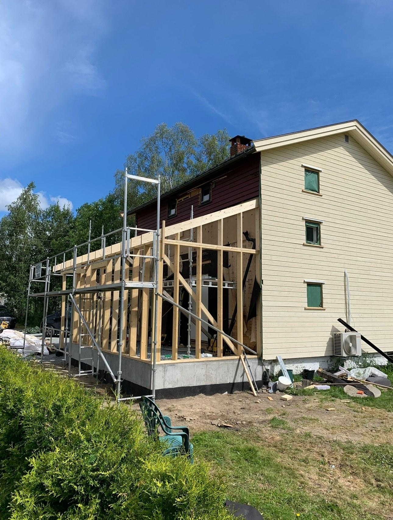 The timber frame of an extension going up beside a yellow house